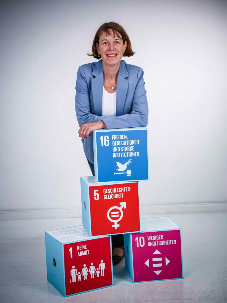 Inga vor einem Block aus Nachhaltigkeitszielen der Vereinten Nationen